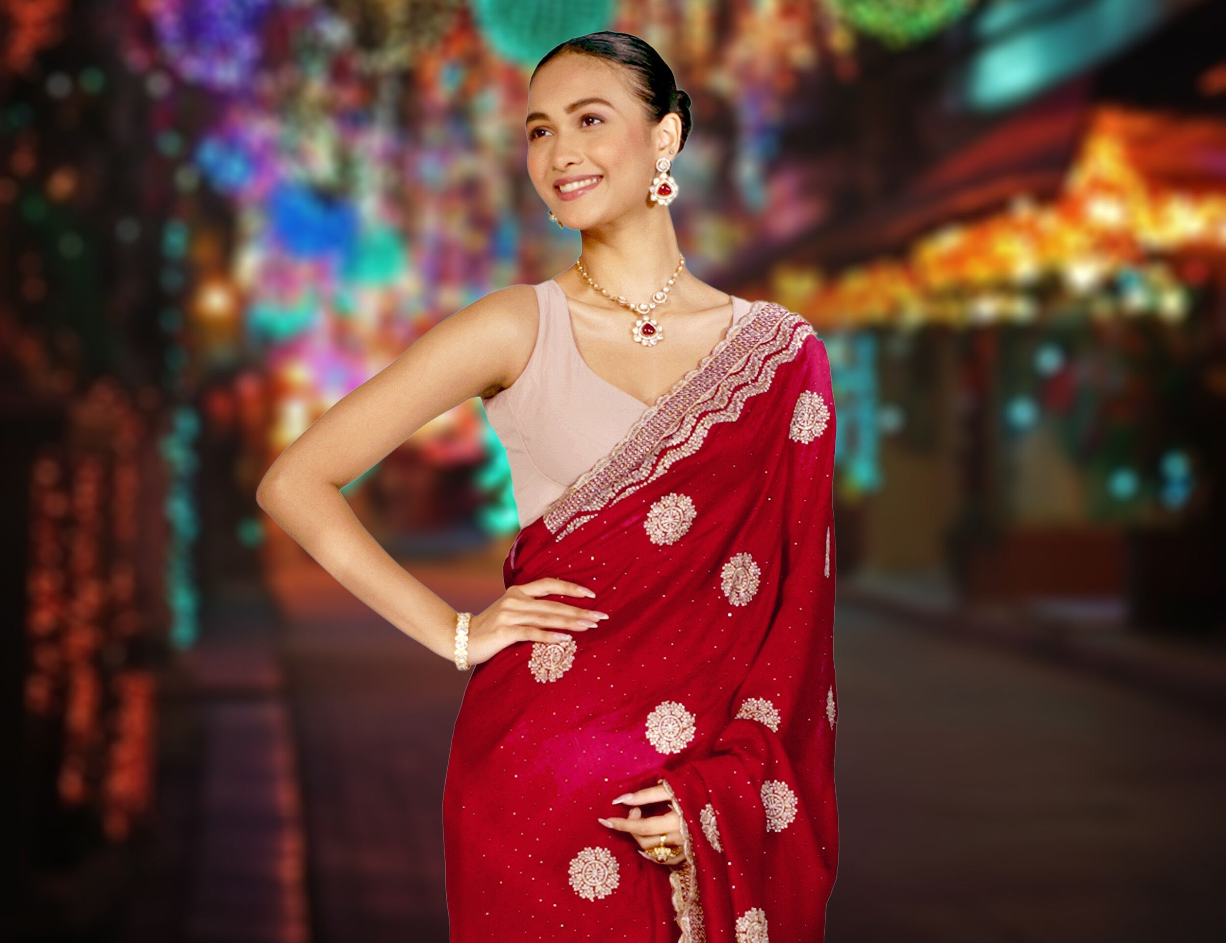 Woman in a red embellished saree with jewelry smiling during Durga Puja festive night celebrations